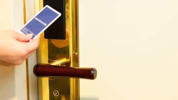 A hand holding a card near a door with a biometric lock and a wooden handle.