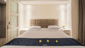 A hotel room with a large bed, a headboard, two bedside tables, and a nightstand. - Alron Hotel Kuta Powered by Archipelago (Kuta)