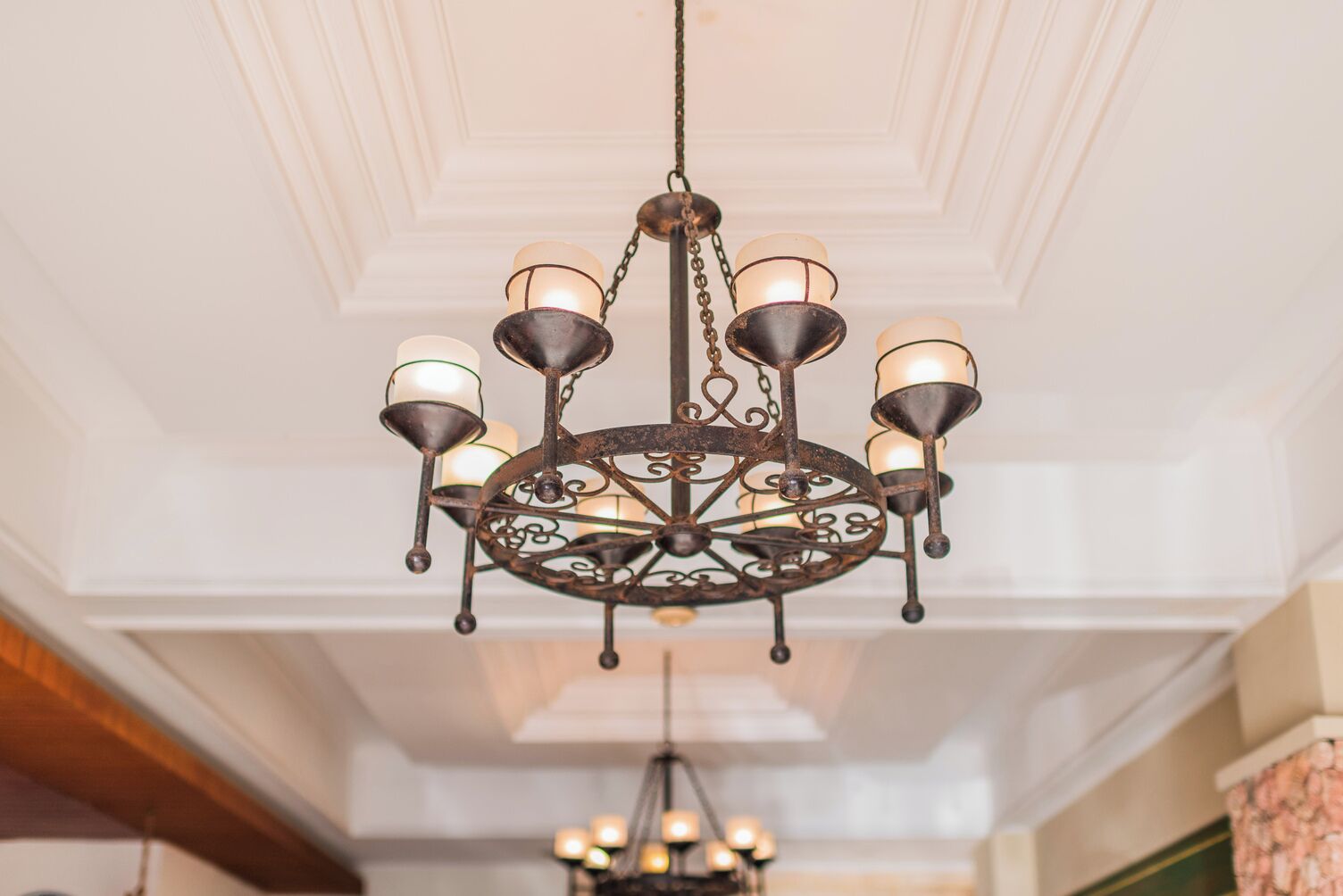 A chandelier with multiple candle-like lights hanging from a decorative metal frame.