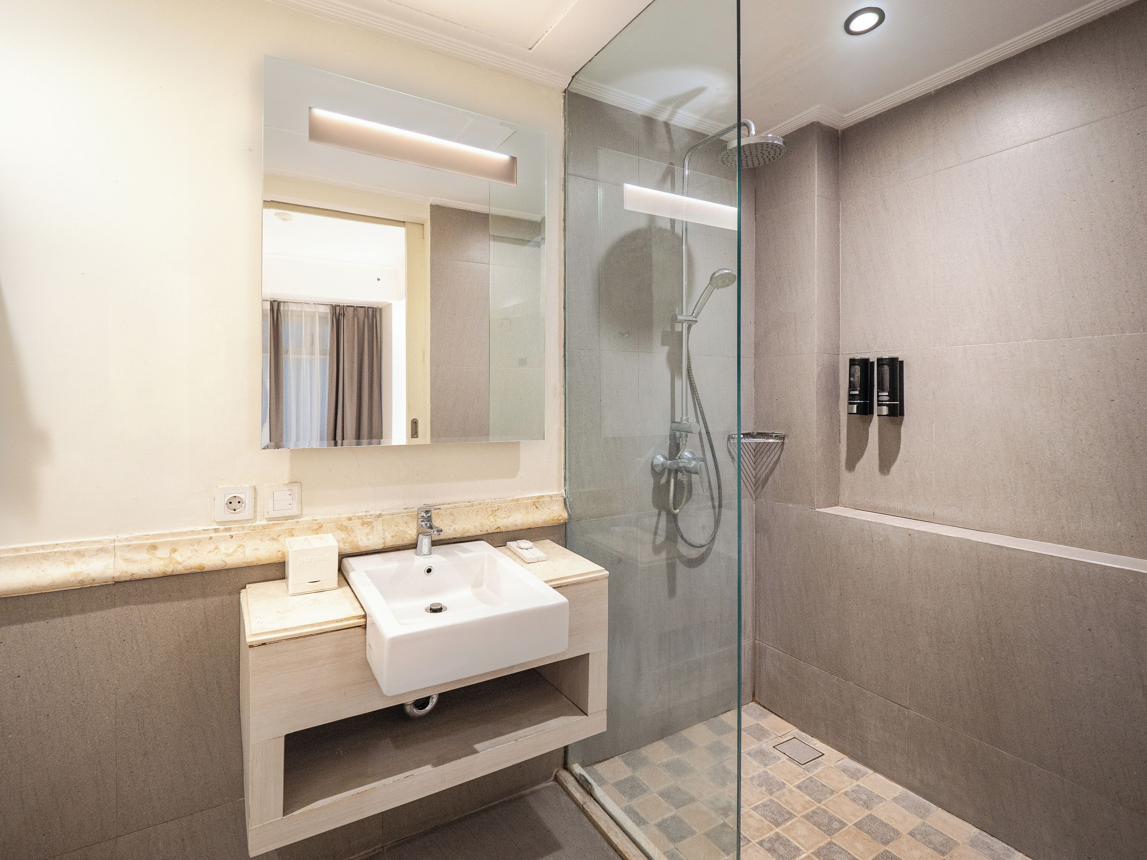 A modern bathroom with a glass-enclosed shower, a white sink, and a mirror above the vanity.