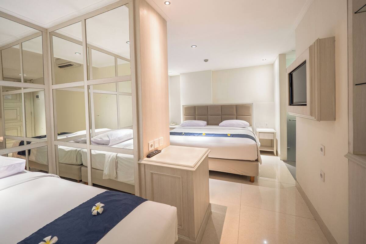 A hotel room with a large bed, a smaller bed, a walk-in closet, a vanity, and a TV mounted on the wall.