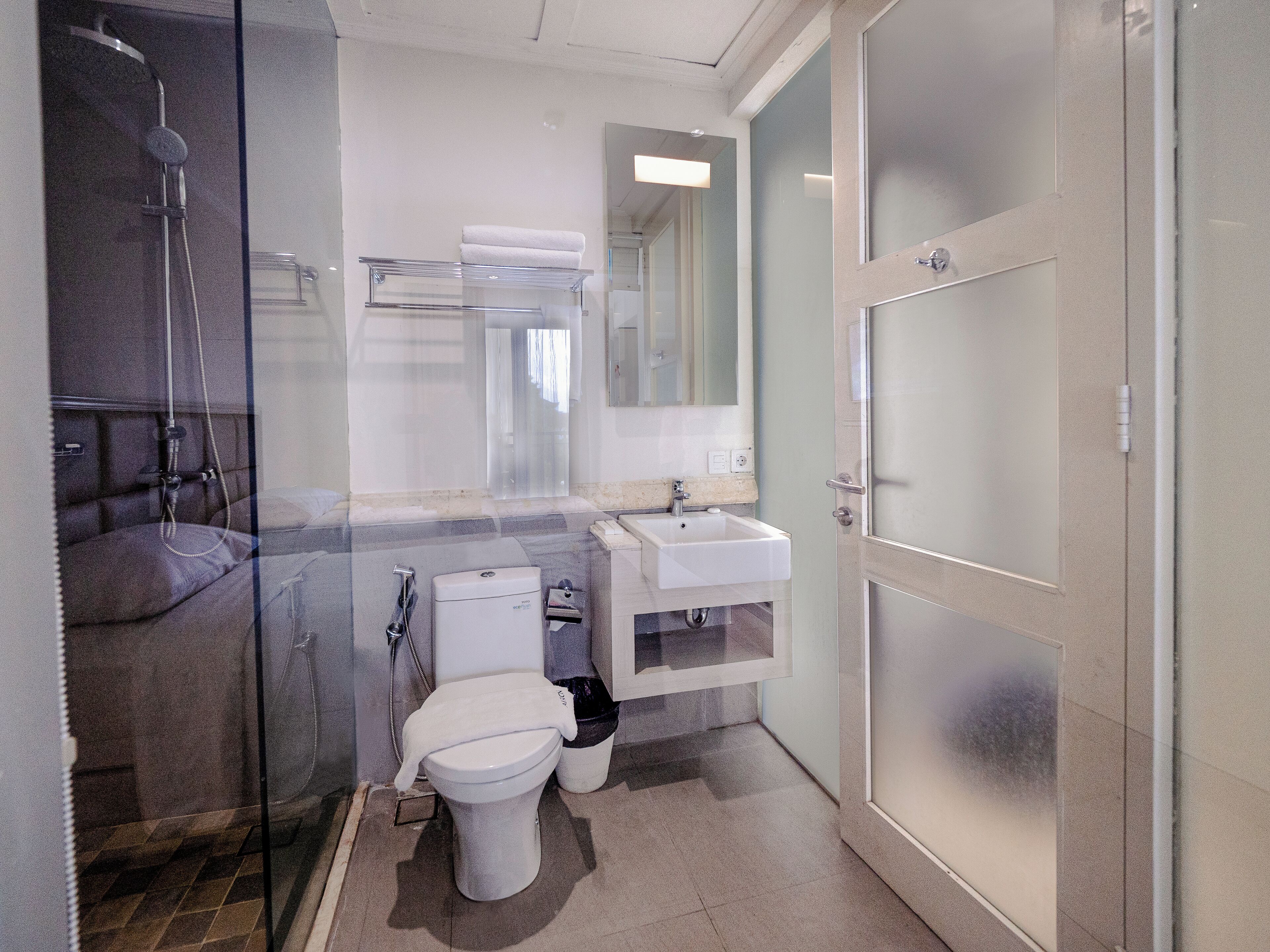 A modern bathroom with a glass shower enclosure, a white toilet, a sink, and a mirror.