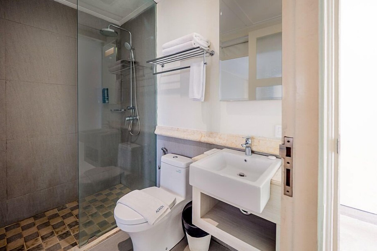 A modern bathroom with a glass shower enclosure, a toilet, a sink, and a towel rack.