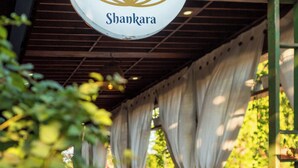 A restaurant named Shankara with a lotus logo, wooden chairs, and a covered outdoor seating area. - Alron Hotel Kuta Powered by Archipelago (Kuta)