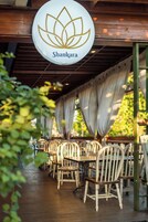 A restaurant named Shankara with a lotus logo, wooden chairs, and a covered outdoor seating area.