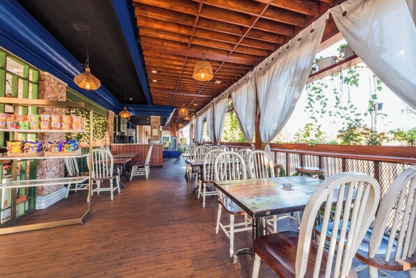 Un restaurant intérieur doté d’un plancher en bois, de chaises blanches et de luminaires suspendus.