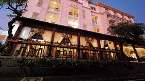 A multi-story hotel with a traditional architectural style, featuring large windows and balconies. - Alron Hotel Kuta Powered by Archipelago (Kuta)