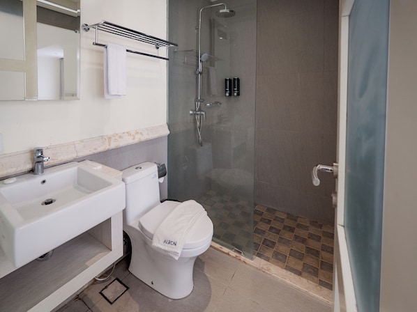 A modern bathroom with a glass-enclosed shower, a white sink, and a toilet with a towel on it.