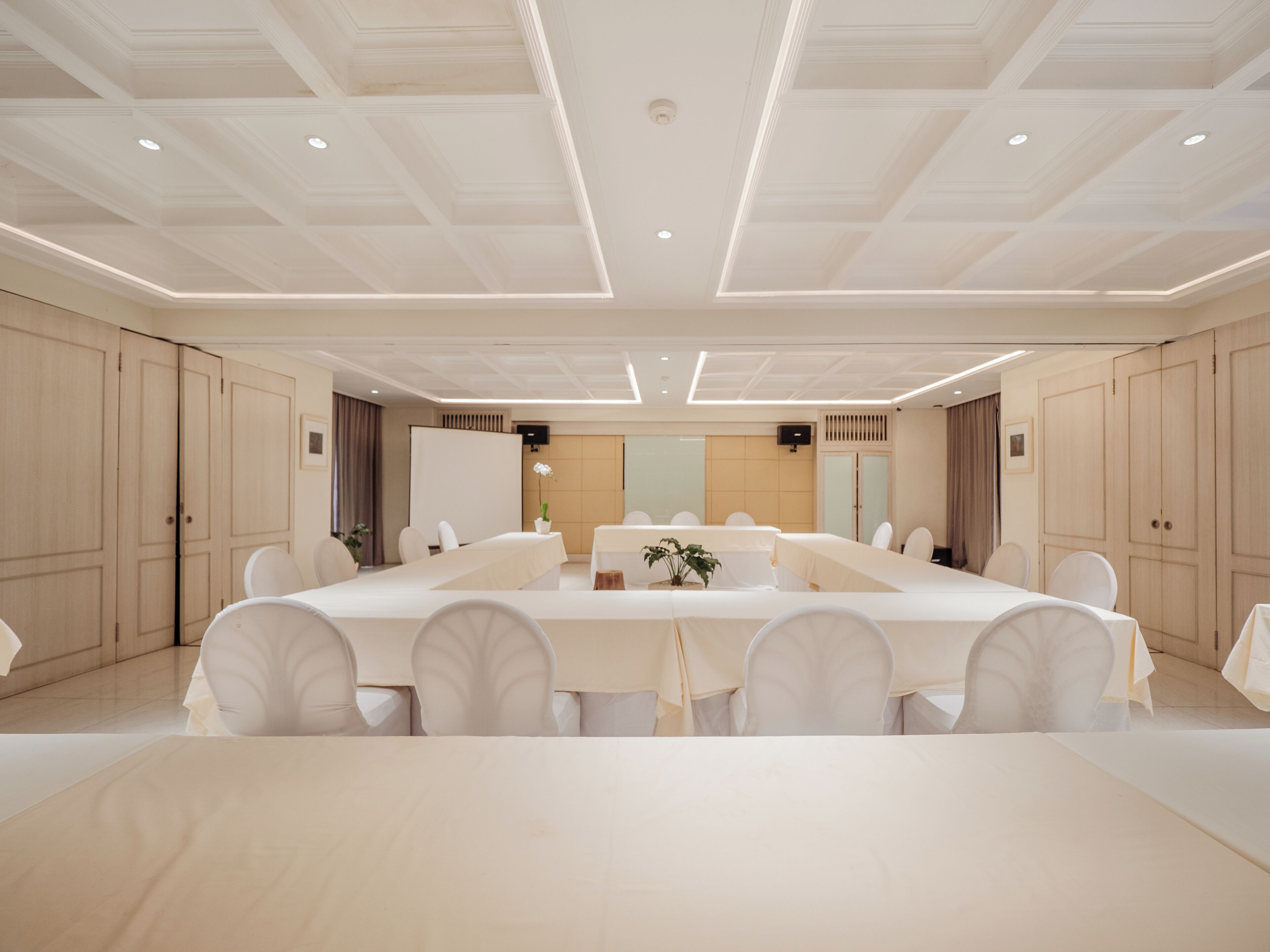 A large conference room with a long table, white chairs, and a neutral color scheme.