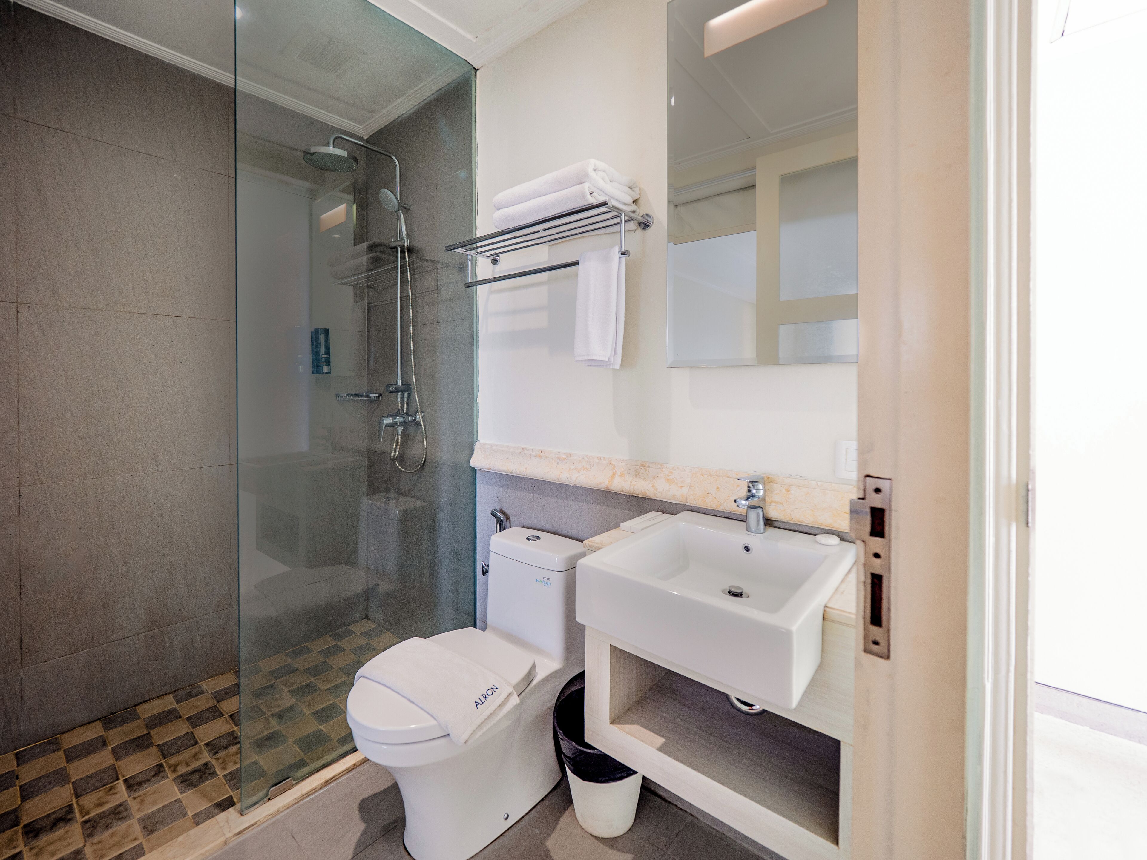 A modern bathroom with a glass-enclosed shower, a toilet, and a sink with a mirror above it.