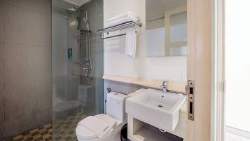 A modern bathroom with a glass-enclosed shower, a toilet, and a sink with a mirror above it.