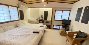 A hotel room with a large bed, a small desk with a chair, a television, and a window with a view. - Guest House Kikusui Ryokan (Tamano)