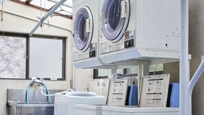 A laundry facility with two washing machines, a sink, and instructional signs. - Guest House Kikusui Ryokan (Tamano)
