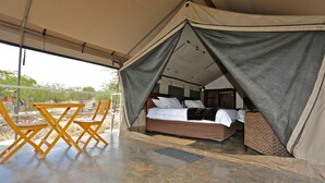 Un alloggio in tenda con un letto, un tavolo e sedie.