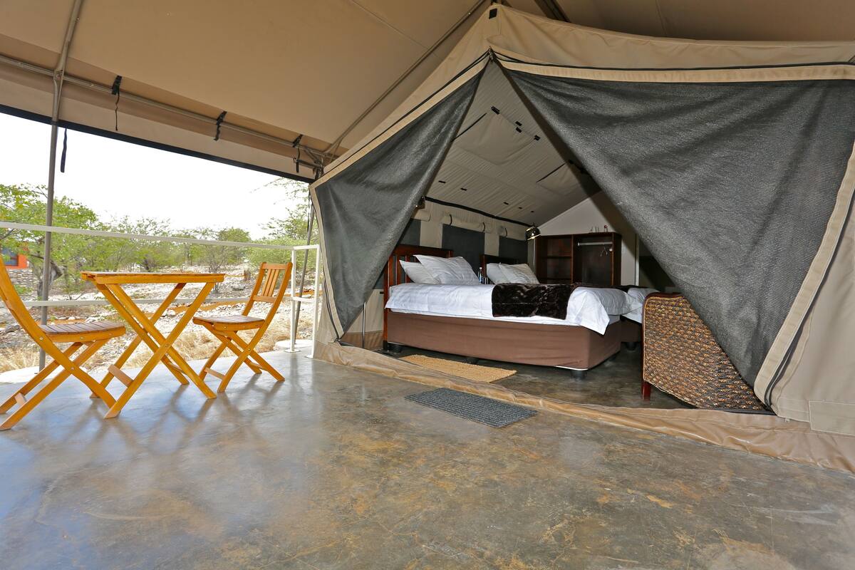 Eine Zelthütte mit Bett, Tisch und Stühlen.