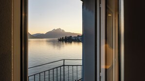 A view from a balcony overlooking a calm lake with mountains in the background. - Hotel Central am See (Weggis)