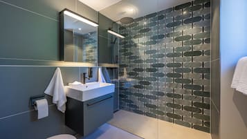 Een moderne badkamer met een douchewand met steenmotief, een wit wastafelmeubel en een toilet.
