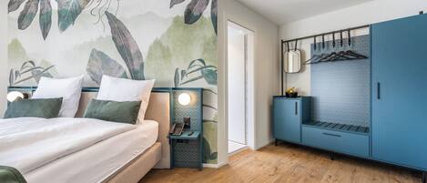 Un dormitorio con cama, mesitas de noche, armario y pared con diseño de hojas.