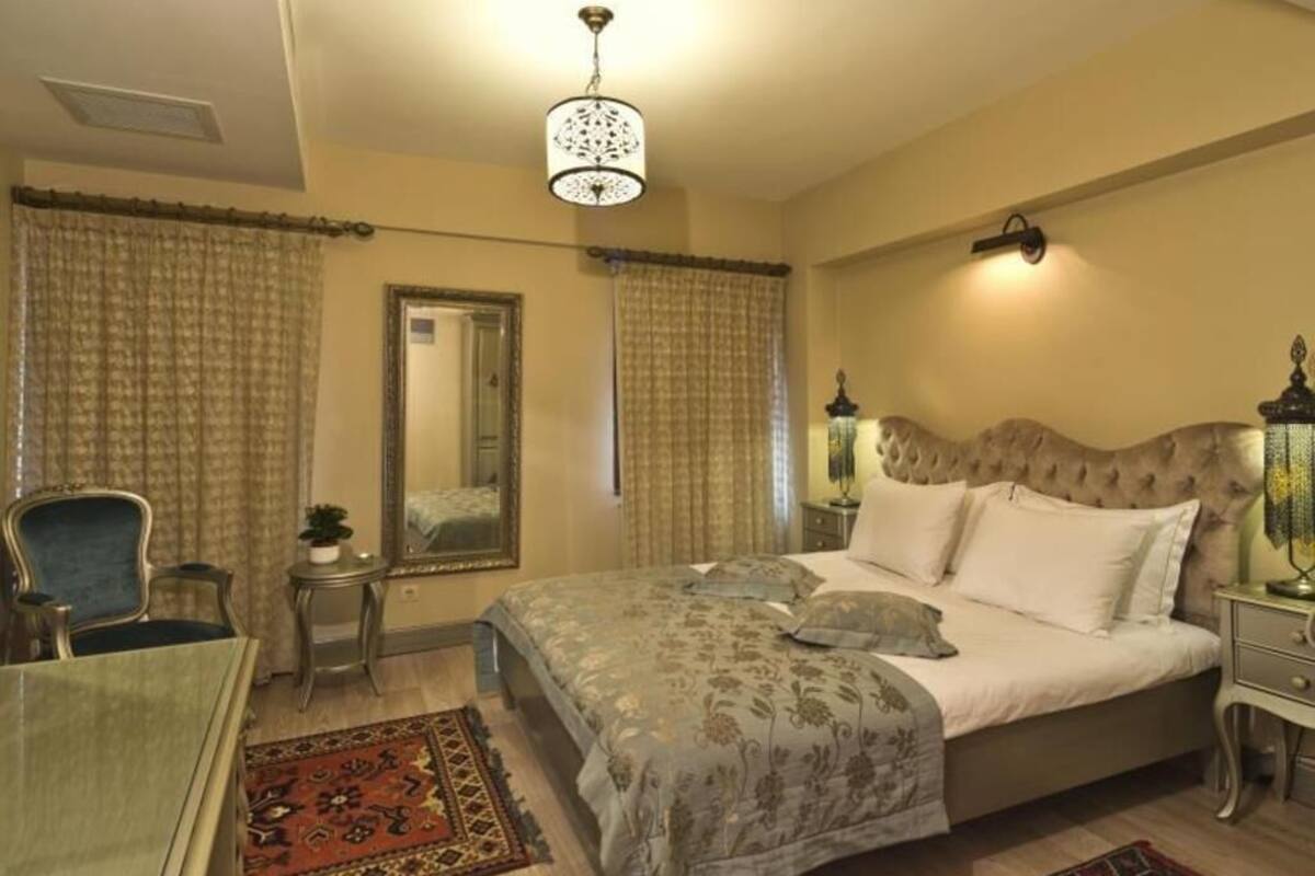 Un dormitorio con cama, una silla, un escritorio, una lámpara y un espejo.