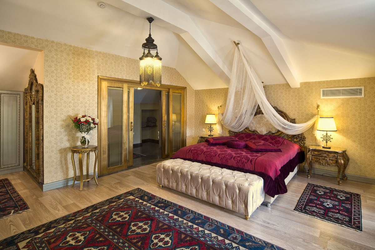 Un dormitorio con una cama grande, dosel, candelabro y diseño tradicional.