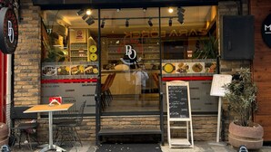 Un restaurant doté d’une façade en verre, d’une terrasse et d’un menu écrit à la craie.