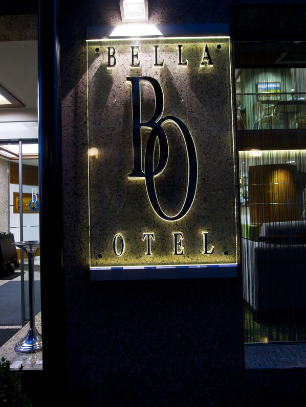 A sign for Bella Hotel with illuminated letters.