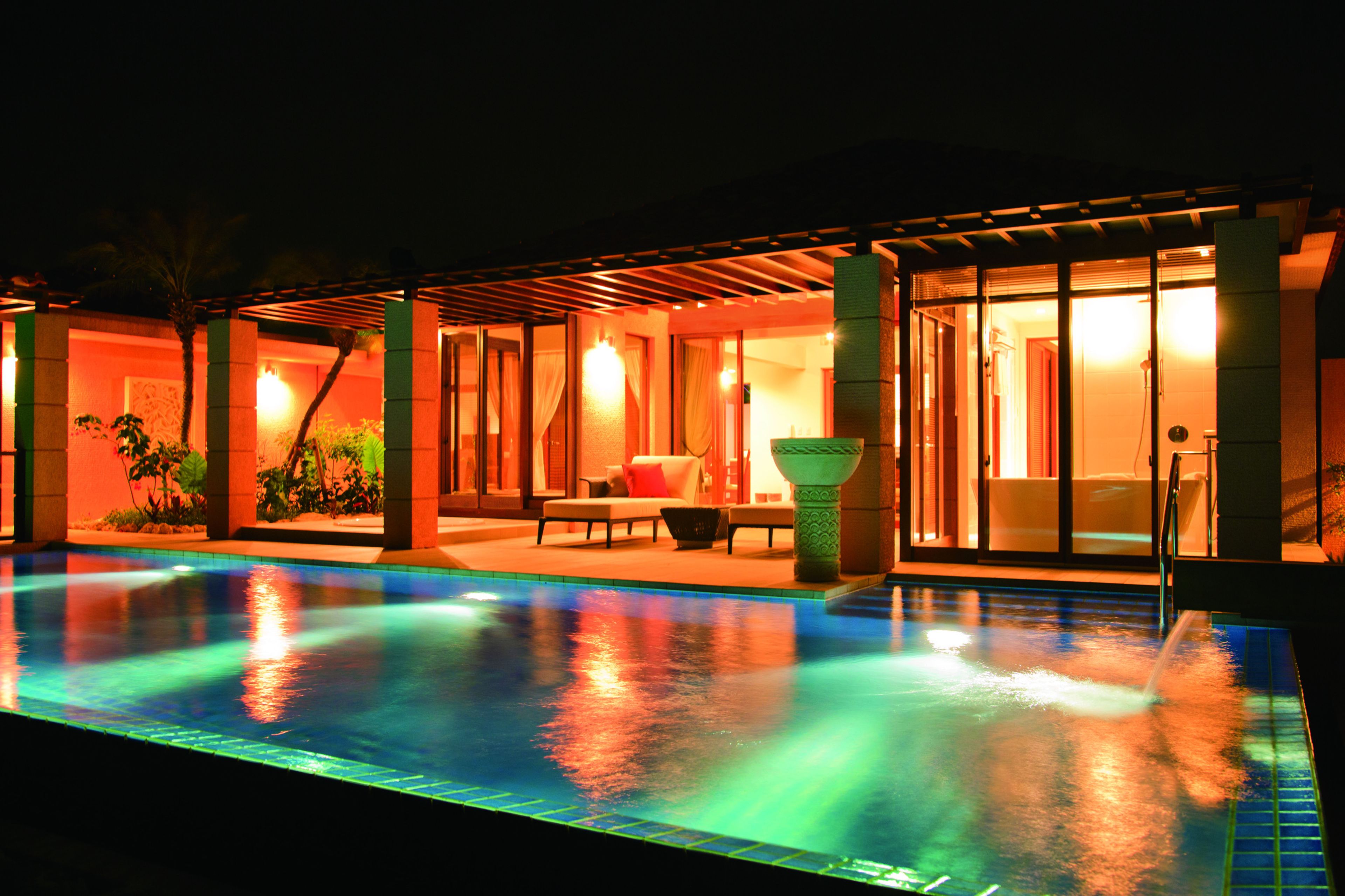 A nighttime pool area with a lounge and a covered seating area.