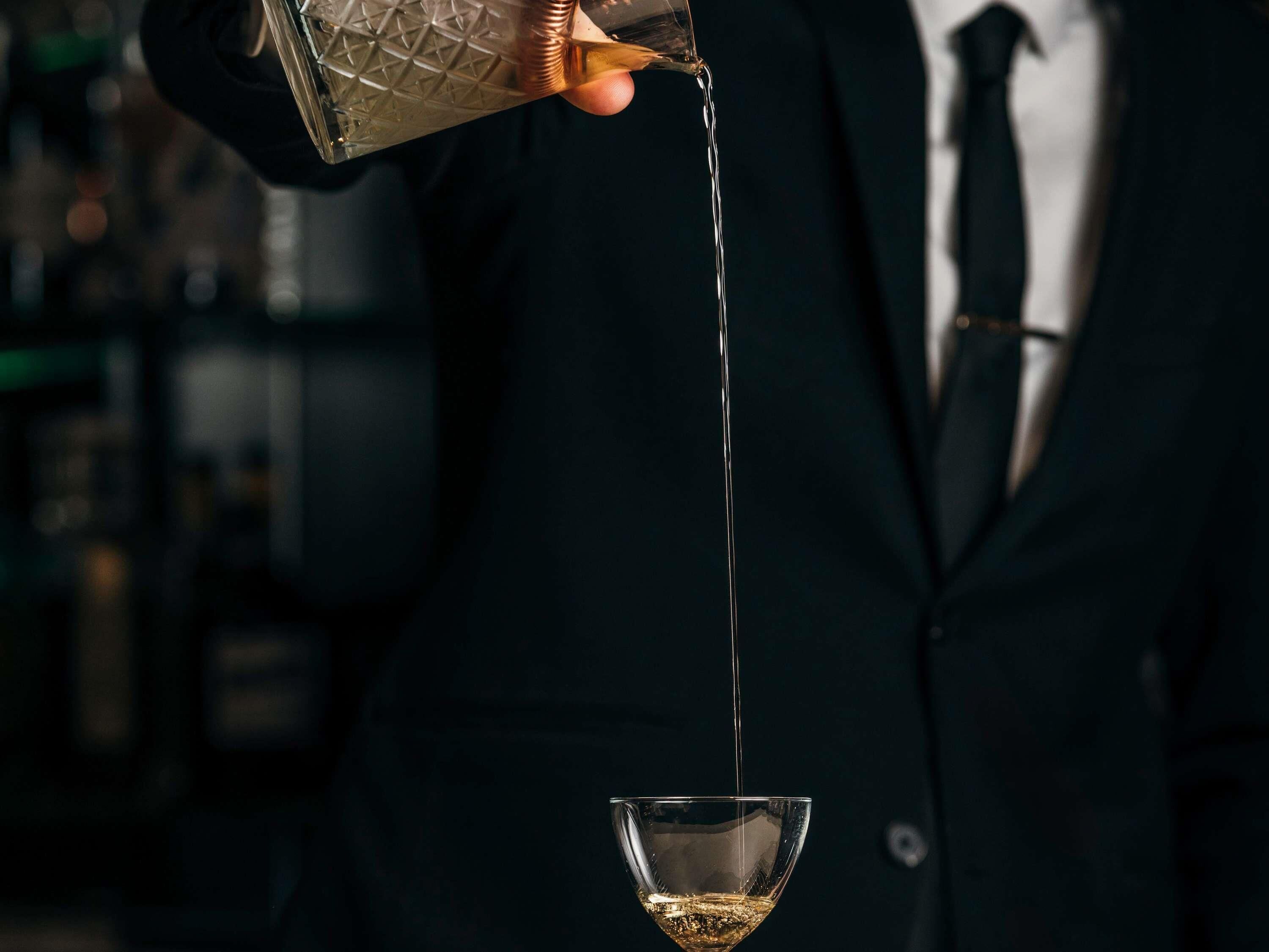 Una persona vertiendo un líquido transparente en un vaso.