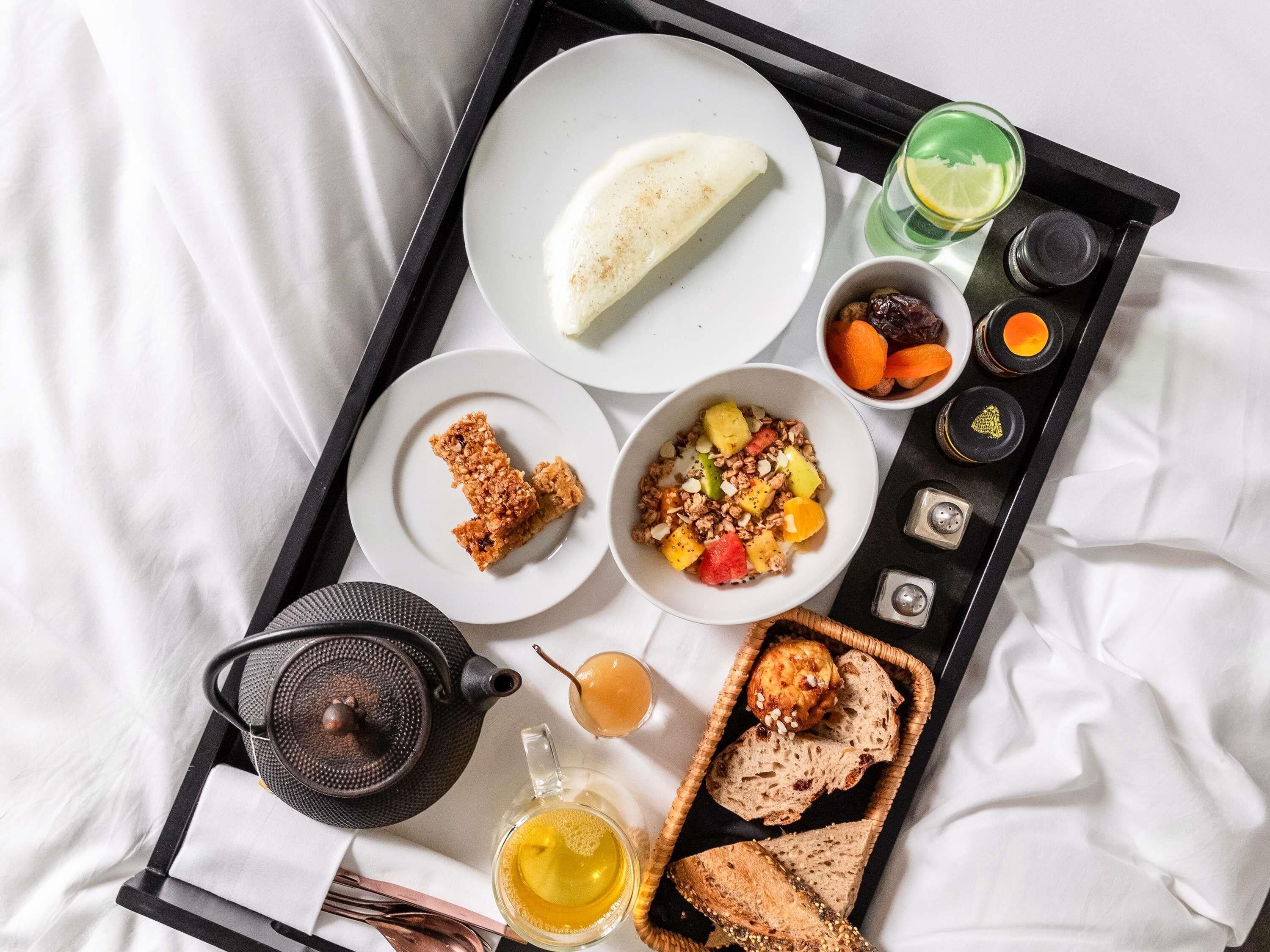 A breakfast tray with a variety of food items including bread, fruit, and a hot beverage.