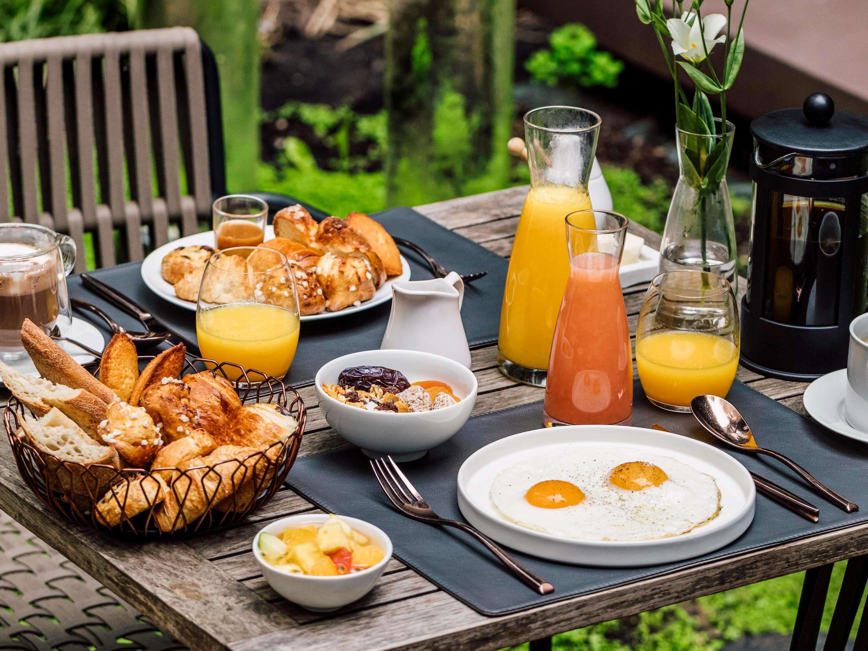 Une table de petit-déjeuner avec des croissants, des œufs et diverses boissons.