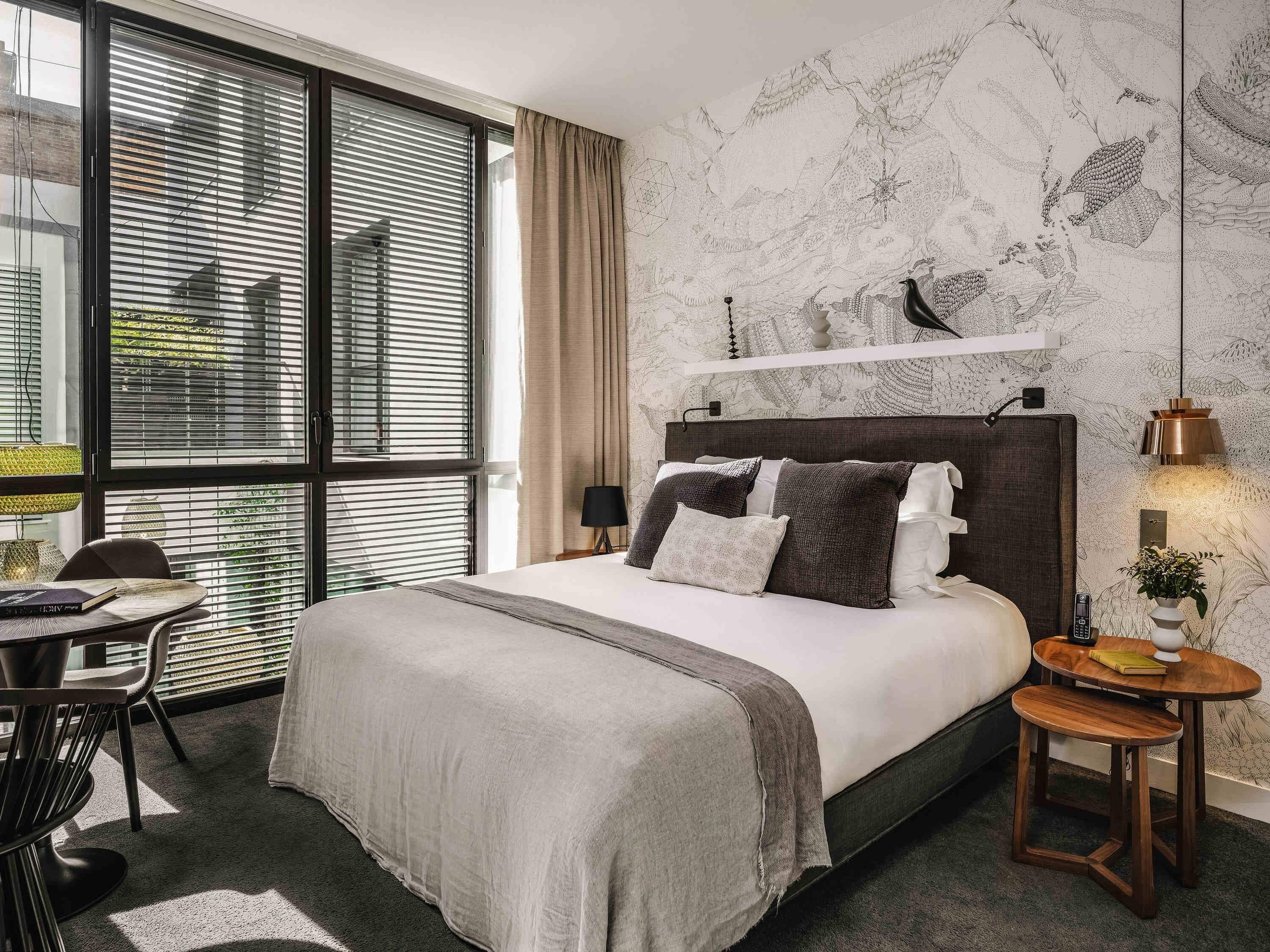 A modern hotel room with a large bed, a desk, and a chair.