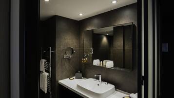 Une salle de bain moderne avec un lavabo blanc, un grand miroir et un porte-serviettes.