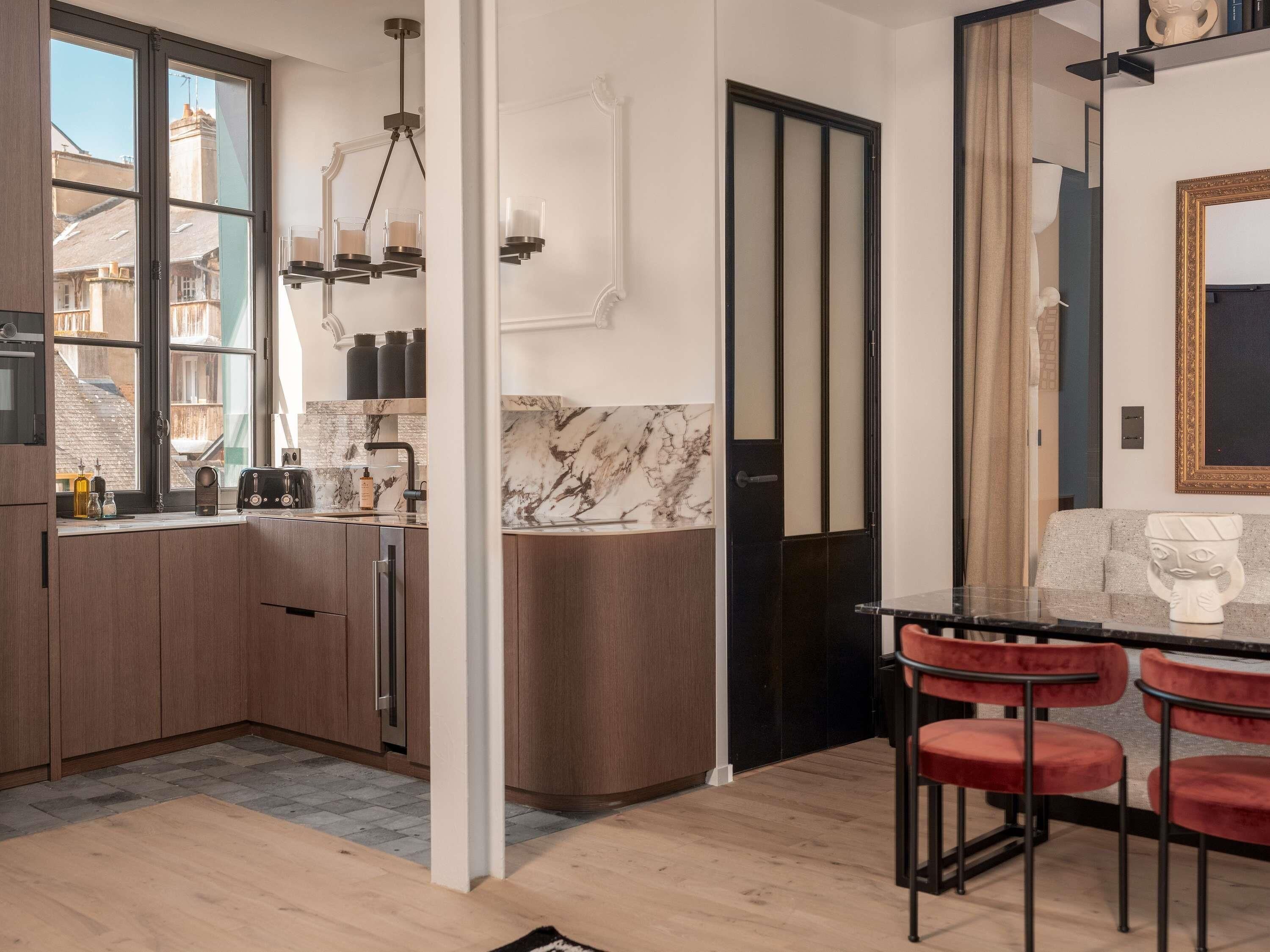A modern kitchen with a marble backsplash, wooden cabinets, and a black-framed mirror.