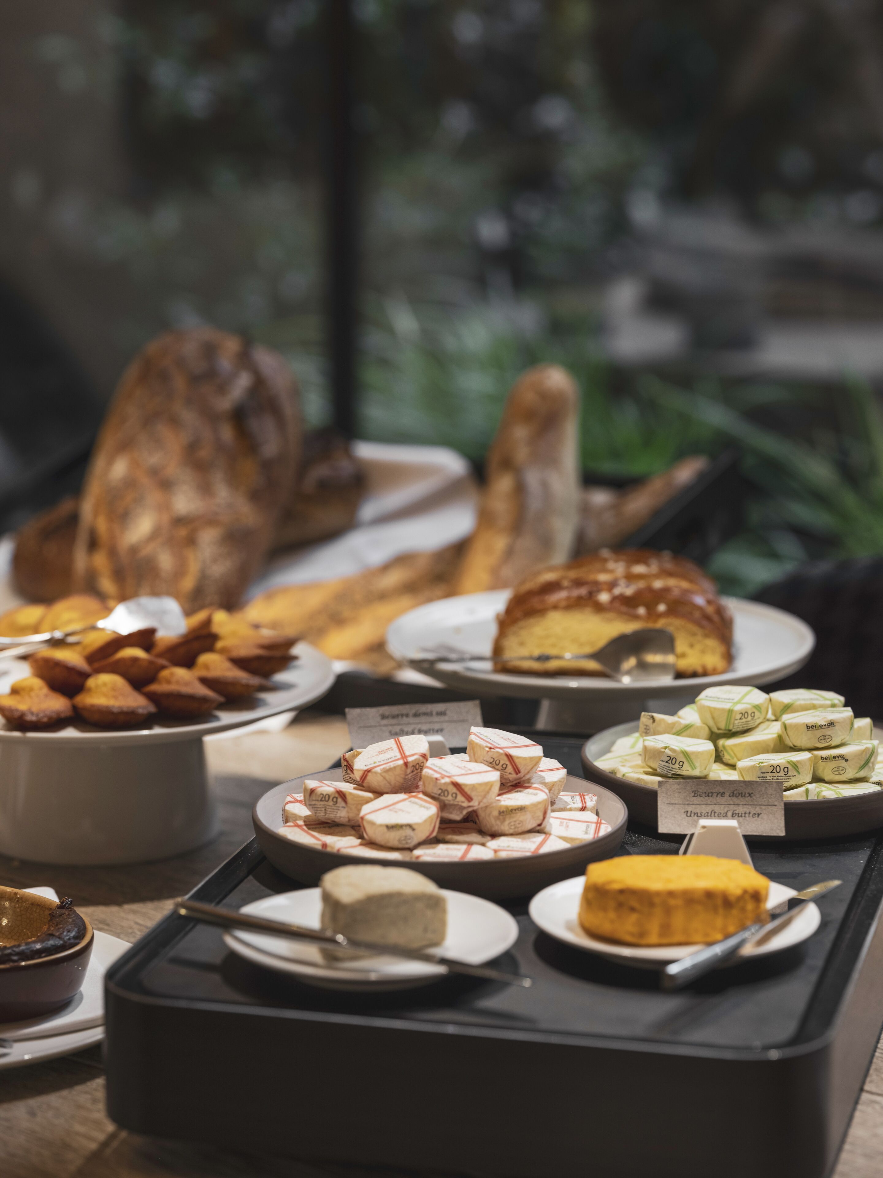Un bufé con diversos alimentos, incluyendo pasteles, pan y queso.