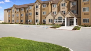 A multi-story hotel with a central entrance, parking lot, and a well-maintained lawn. - Microtel Inn & Suites by Wyndham Kenedy/Karnes City (Kenedy)