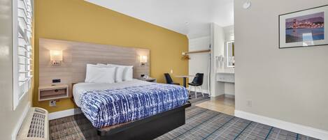 Een hotelkamer met een bed, nachtkastjes, een stoel, een tafeltje en een schilderij aan de muur.