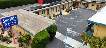 Una posada frente al mar con estacionamiento, un letrero que indica habitaciones disponibles y un edificio con techo plano.