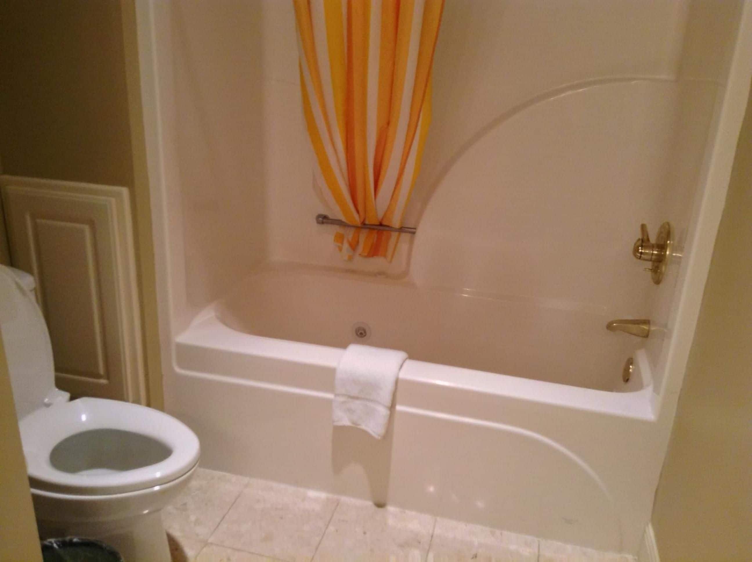 Un baño con bañera, inodoro y cortina de ducha.