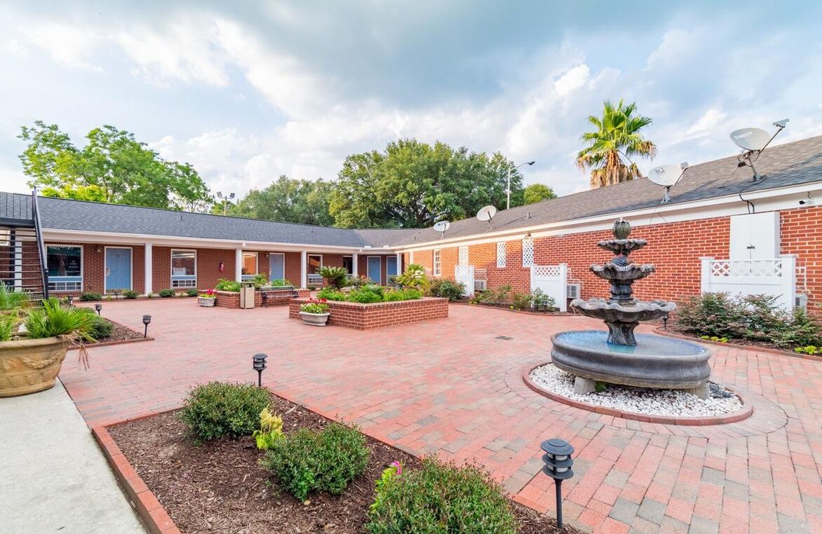 A courtyard with a fountain, brick buildings, and satellite dishes.