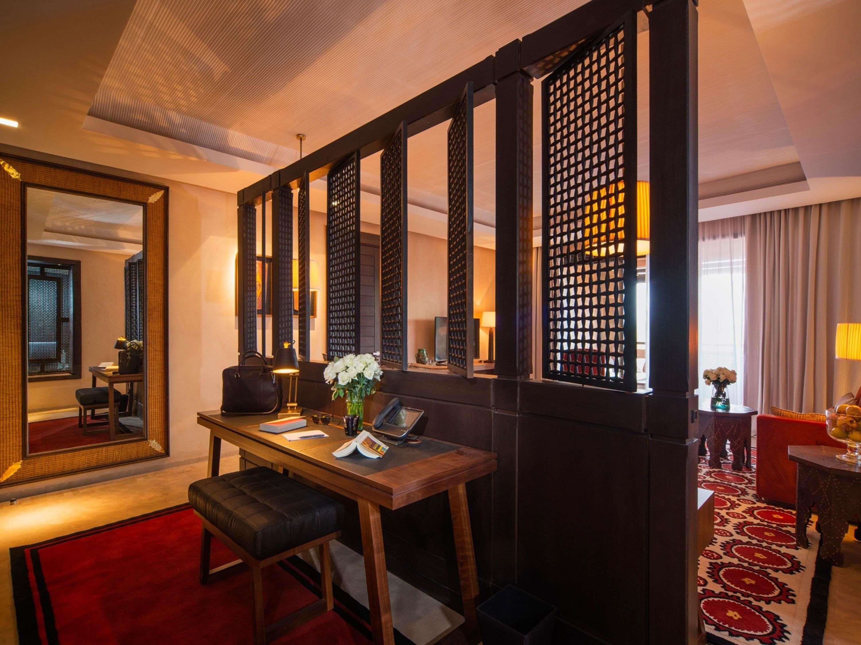 A hotel room with a desk, chair, and a large mirror.