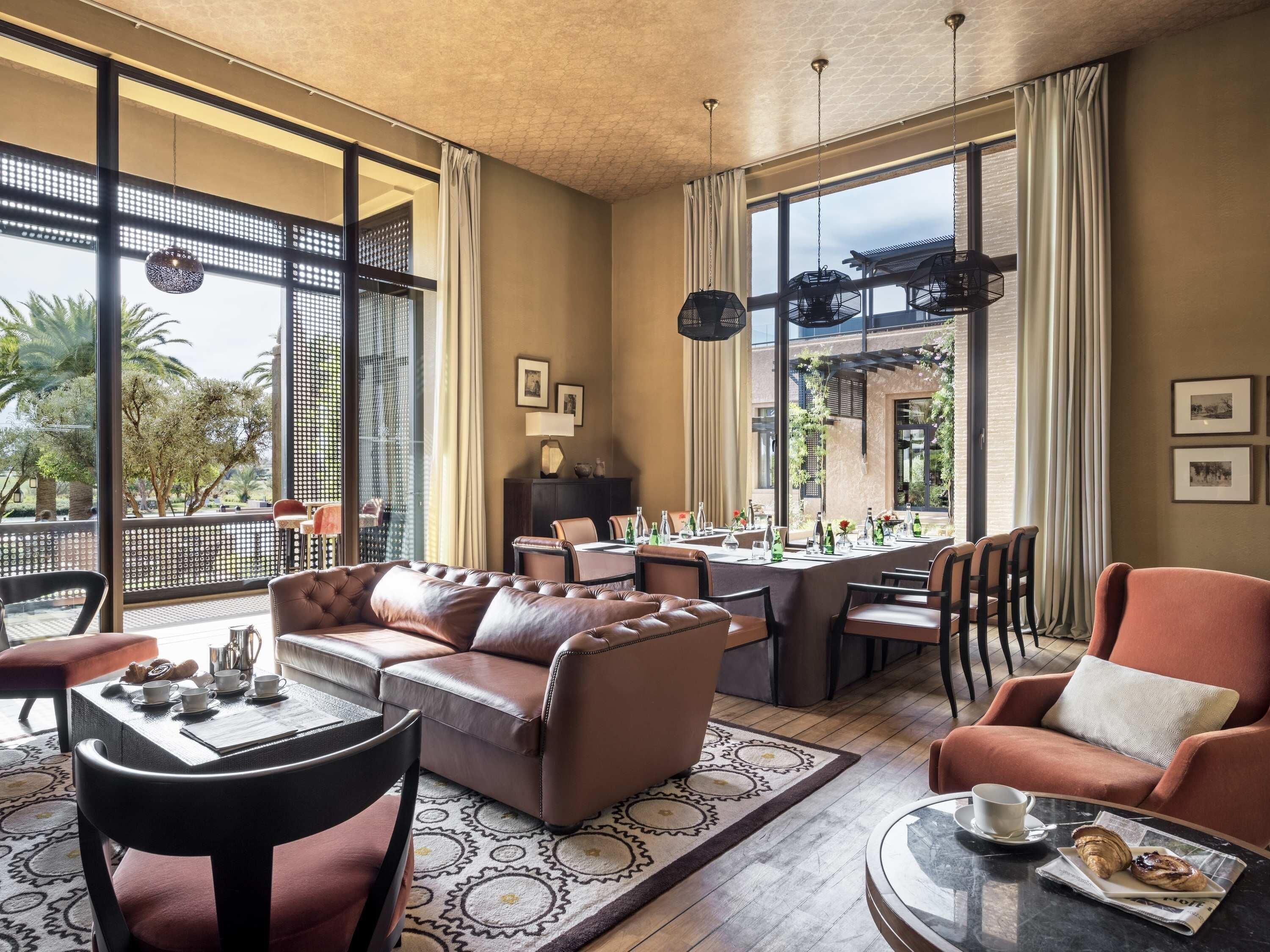 Una habitación amplia con un sofá de cuero, una mesa de comedor, sillas y una mesa auxiliar.