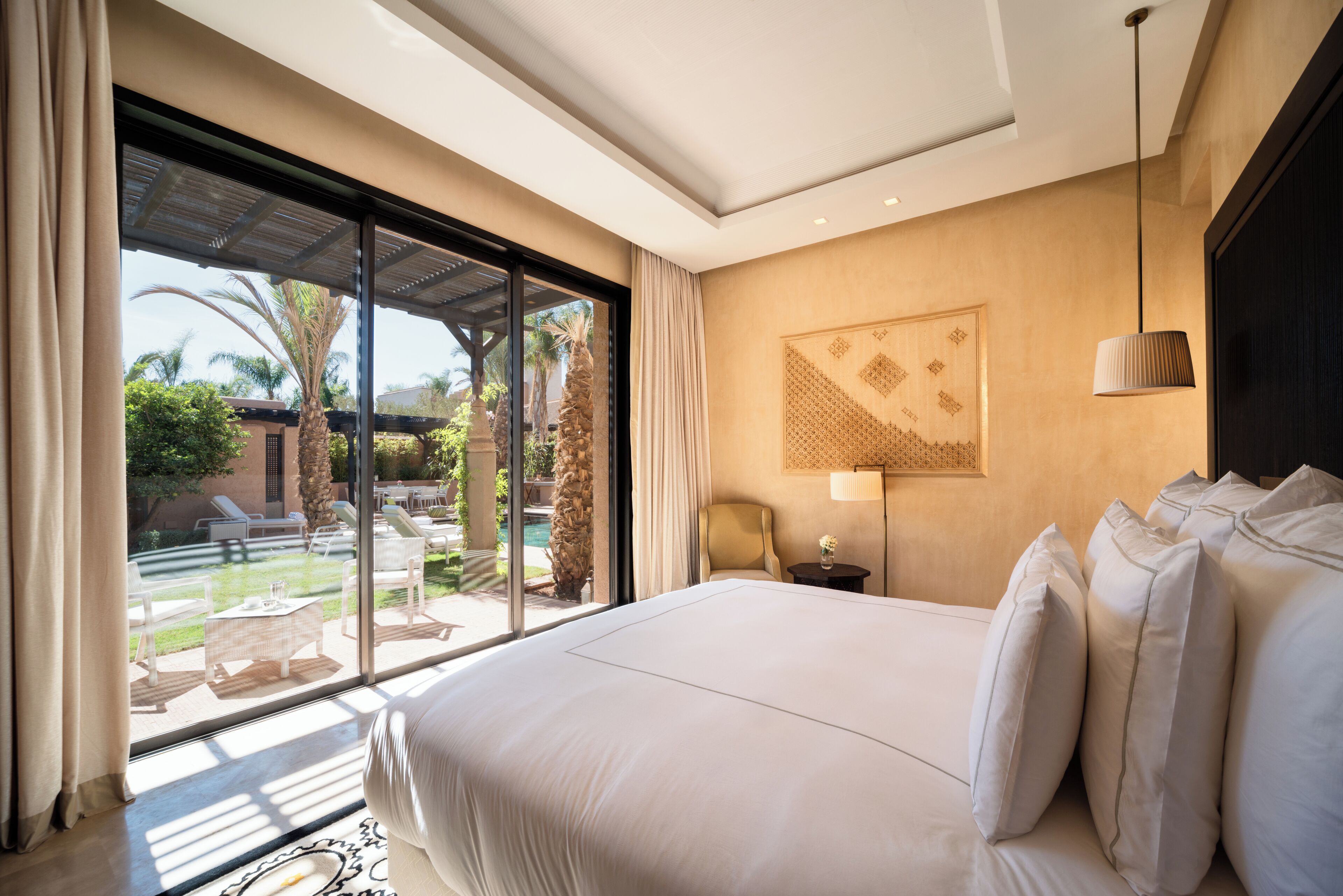 Una habitación de hotel con una cama grande, vistas a la piscina exterior e iluminación empotrada en el techo.
