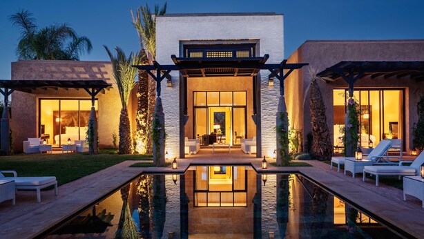 Un resort moderno con piscina, zona de estar exterior e ingreso bien iluminado.