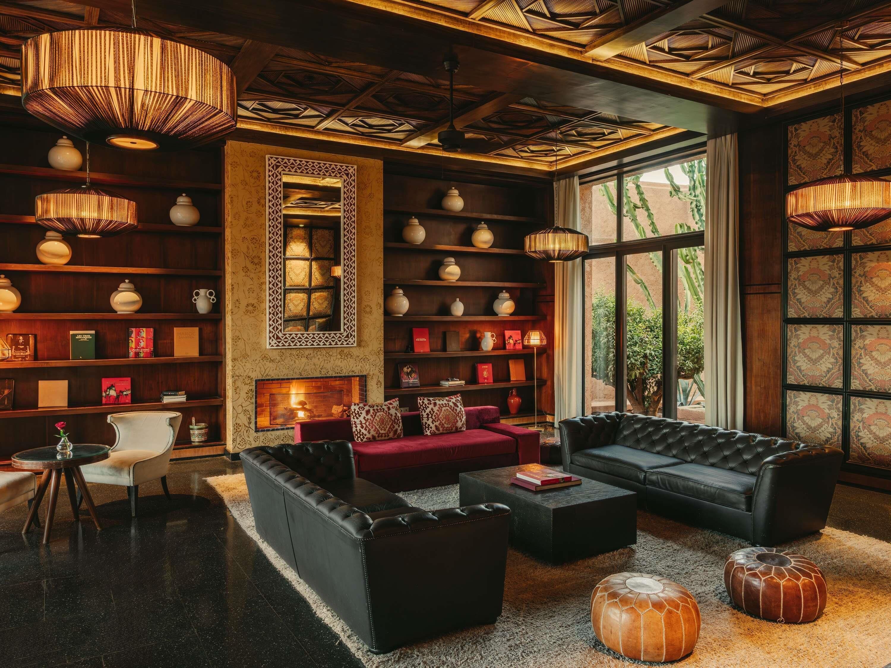Uma área de estar aconchegante com lareira, sofás de couro e uma estante repleta de livros e objetos decorativos.