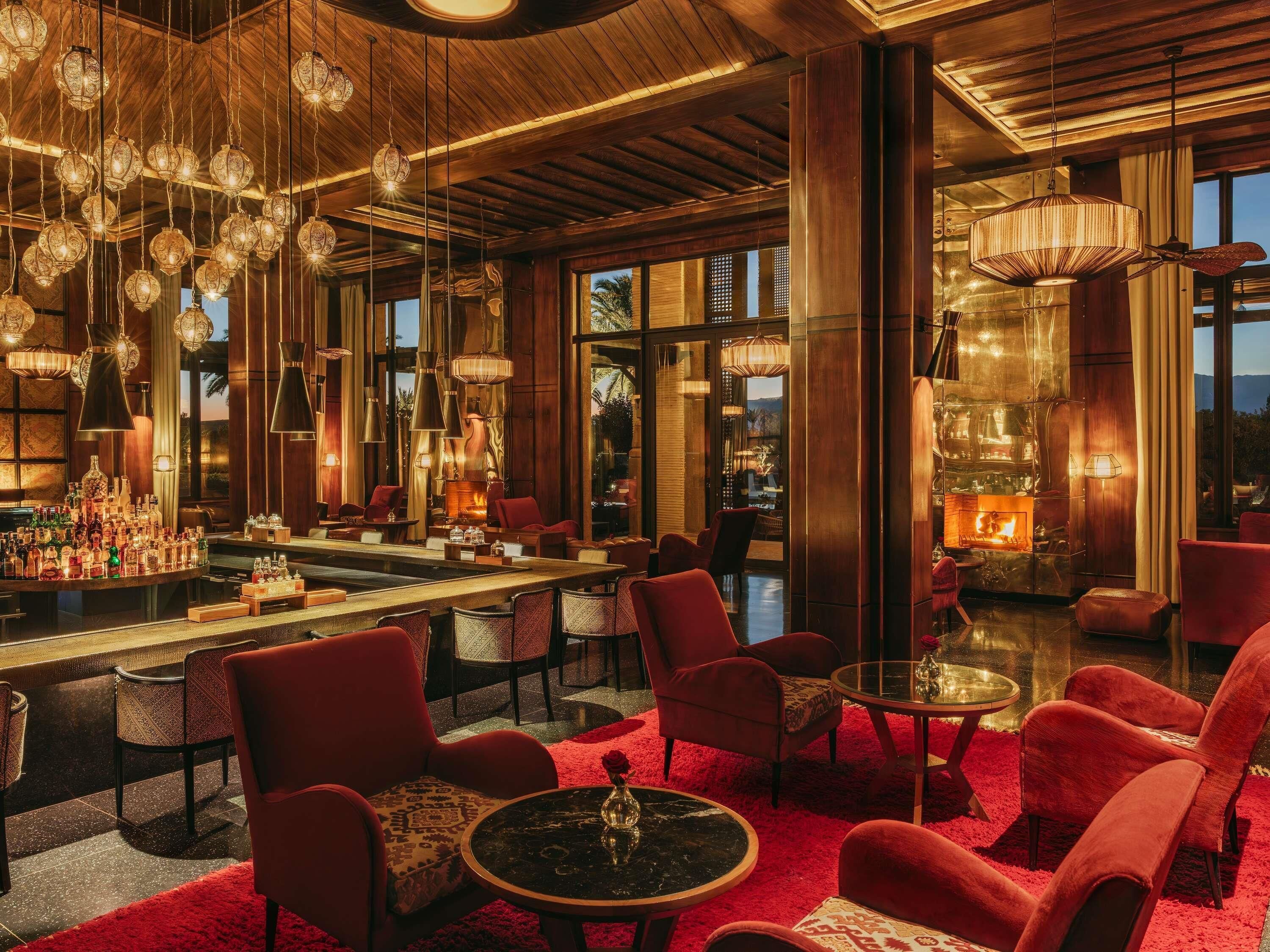A bar area with a variety of seating options, including red upholstered chairs and round tables.