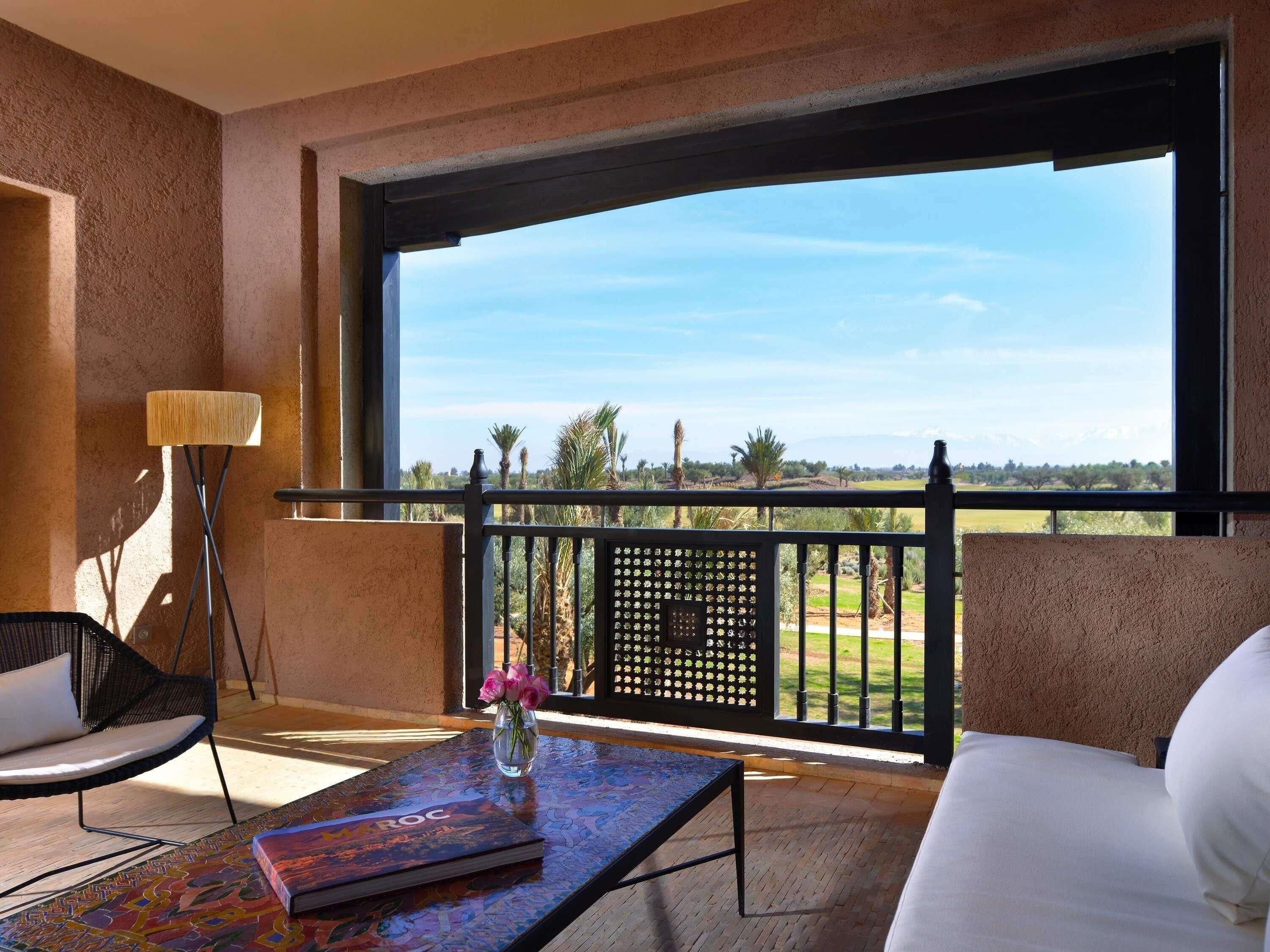 Un balcón con vista a un paisaje, un sofá, una silla, una mesa y una lámpara.