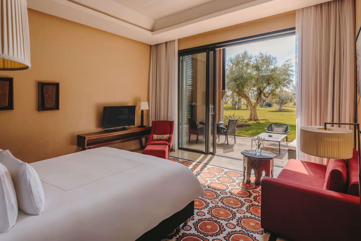 Une chambre d’hôtel équipée d’un lit, d’une télévision, d’un bureau, d’une chaise, d’un canapé et offrant une vue sur l’extérieur.