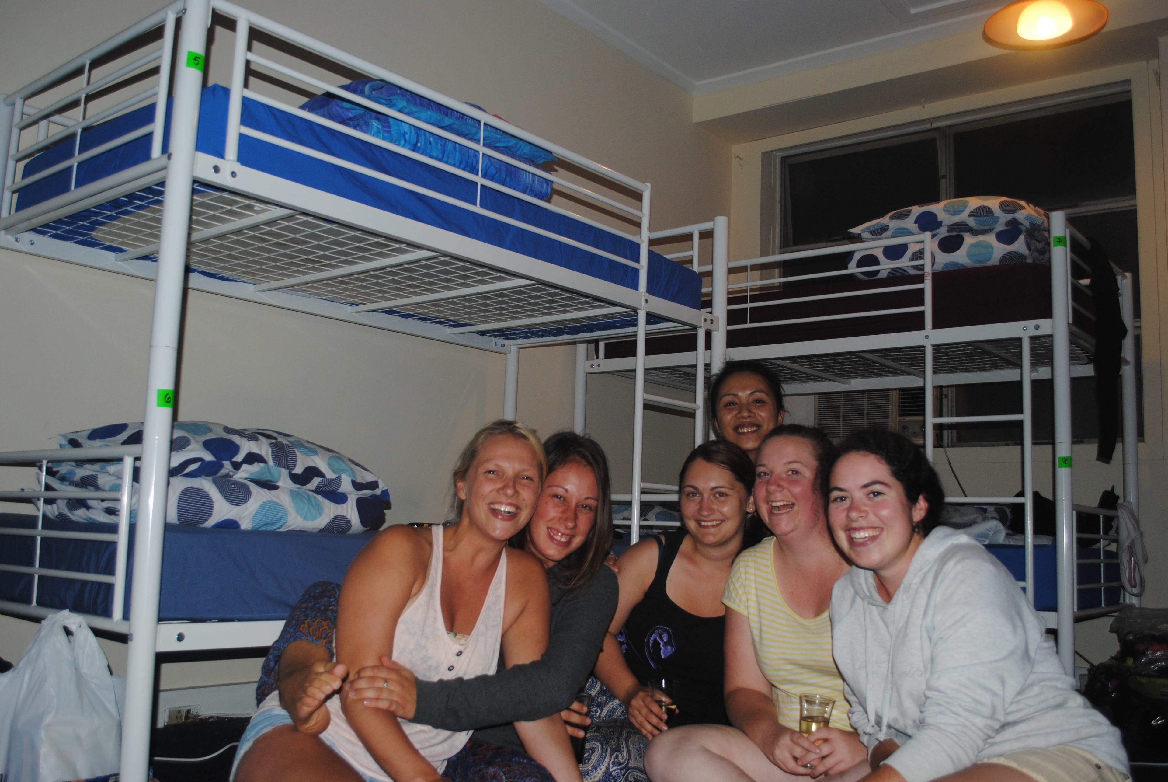A bunk bed room with four people sitting on the lower bunk.