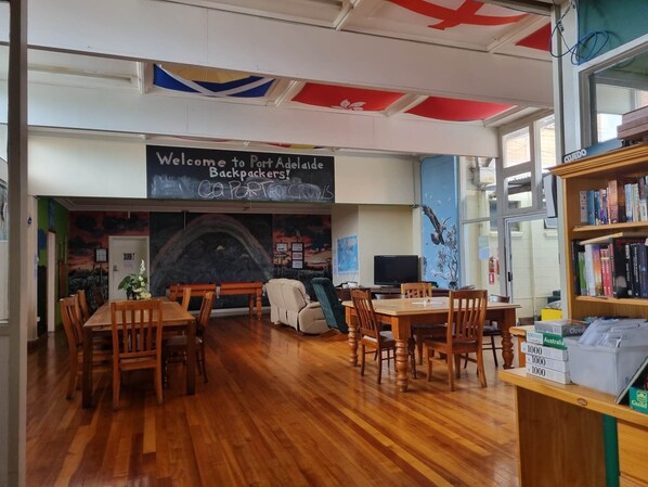 Una biblioteca con mesas y sillas de madera, una chimenea y una estantería llena de libros.