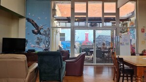 Una habitación con televisión, un sofá, una silla, una mesa de comedor y vistas al exterior a través de una puerta de cristal.